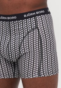Črne bokserice z geometrskim vzorcem v beli, sivi in črni barvi. Elastičen pas z blagovno znamko "BJÖRN BORG". Mehka, raztegljiva tkanina.