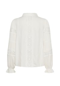 Blouse blanche à manches longues avec inserts en dentelle sur les manches et le dos, dotée d'un col et de poignets élastiques à volants.