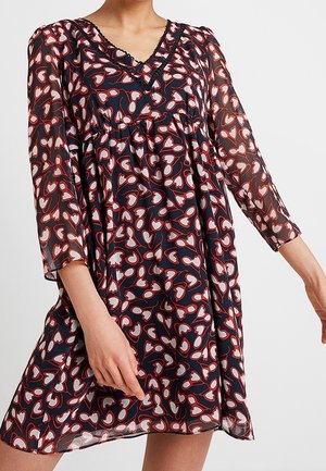 Robe en tissu transparent de couleur marine avec un motif de cœurs rouges et blancs, décolleté en V, manches trois-quarts et taille froncée. Finition détaillée au niveau du décolleté.