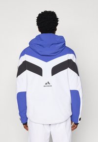 Sinine ja valge jakk mustade aktsentidega, kapuutsiga, chevron-mustriga ja logoga. Valmistatud siledast, ilmastikukindlast materjalist.