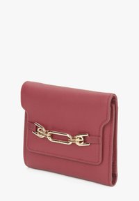 Červená kožená peněženka s akcentem ze zlatého řetízku, sklápěcí klapkou a prošívanými okraji. Kompaktní obdélníkový tvar s hladkým povrchem.