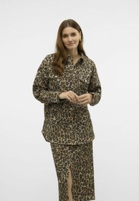 Læderjakke med leopardprint og to brystlommer, brune nuancer, og lange ærmer, parret med en knælang nederdel med en sideslids.