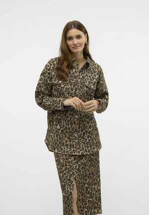 Giacca camicia con stampa leopardata, dotata di due tasche sul petto, in tonalità marroni e maniche lunghe, abbinata a una gonna al ginocchio con spacco laterale.