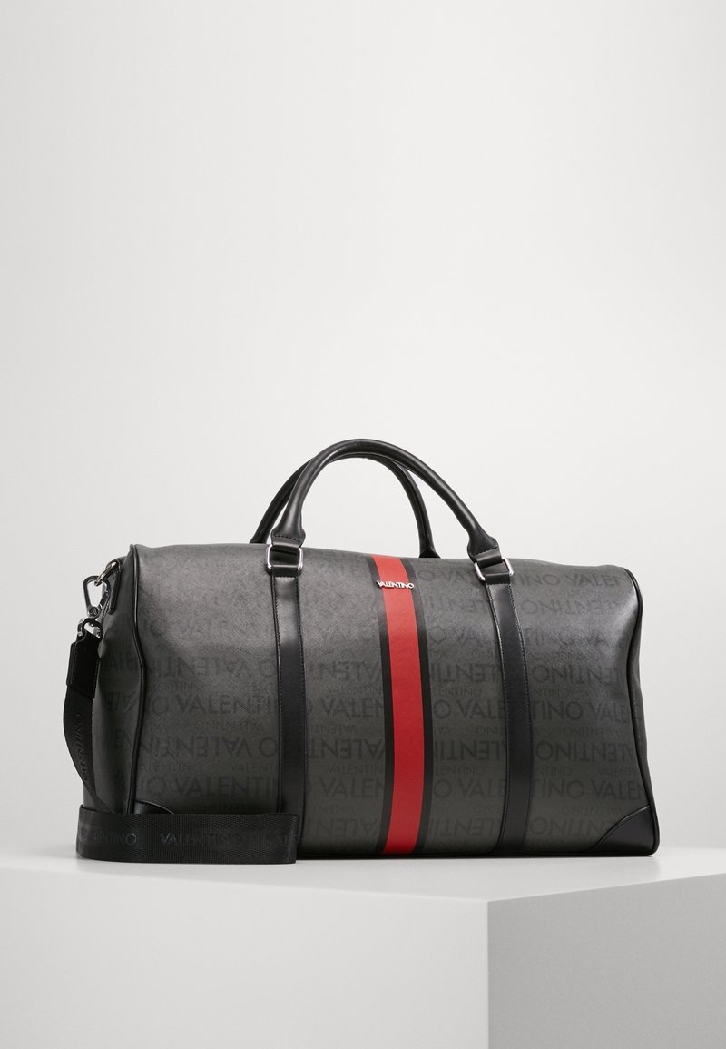 Svart skinn duffelbag med rød aksentstripe og preget logo-mønster, med topphåndtak og justerbar skulderrem.