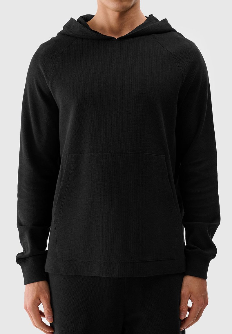 Schwarzer Kapuzenpullover mit geripptem Struktur, vorderer Kängurutasche und langen Ärmeln. Hat eine lockere Passform und ein minimales Design.