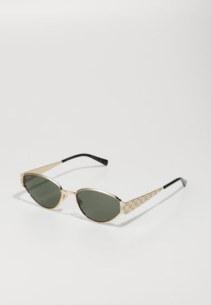 Gold cat-eye sunglasses with green lenses, featuring a textured GG pattern on the temples and sleek black tips for added contrast.