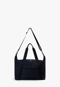 Bolsa de lona azul marino con dos asas superiores y una correa de hombro desmontable. Cuenta con un bolsillo frontal y una marca minimalista.