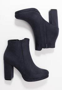 Dark blue ankle boots made of suede, featuring a high block heel, rounded toe, and a side zipper for easy wear. Smooth texture, minimalist design.