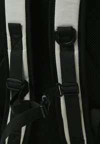 Schwarze Rucksackträger mit Mesh-Struktur, verstellbaren Schnallen und einer Mischung aus einfarbigen und weiß akzentuierten Paneelen. Robuste Materialien sind verarbeitet.