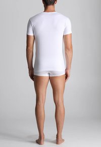 T-shirt bianca a maniche corte e slip bianchi, realizzati in cotone morbido. Design aderente, texture leggera e costruzione semplice.