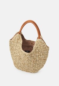 Geweven rieten draagtas met een gebogen vorm, natuurlijke beige kleur, bruine leren handvatten en een stoffen interieur met een zichtbaar label.