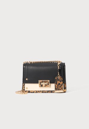 Sac à main en cuir noir avec des accents en imprimé léopard. Il dispose d'une bandoulière en chaîne dorée et d'un fermoir, ainsi qu'une étiquette de bagages décorative sur le côté.