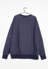 Tmavě modrý svetr s dlouhým rukávem zavěšený na černém ramínku na bílém pozadí, ukazující zadní stranu.