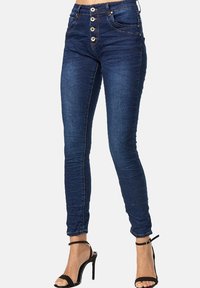 Jean ajustados de color azul oscuro con cintura alta, que cuentan con un cierre de cinco botones, bolsillos frontales y un ajuste elegante. Textura de denim suave.