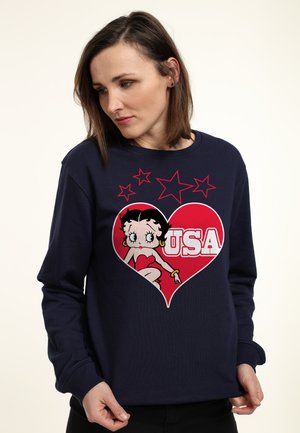 Marineblå sweatshirt med et rødt hjertegrafik, der viser en tegneseriefigur og teksten "USA." Lange ærmer og rund halsudskæring.