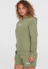 Olivgrüner Hoodie und passende Shorts aus weicher Baumwolle, mit Kängurutasche, gerippten Bündchen und weißen Logodetails.