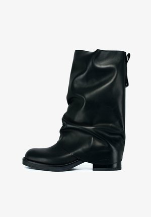 Czarne skórzane buty do połowy łydki o luźnym kroju, okrągłym czubku, płaskiej podeszwie i uchwycie z tyłu.