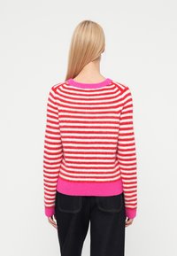 Punase ja valge triibuline kampsun roosa soonikkoelise krae ja äärega. Pehme tekstuur, pikad varrukad ja liibuv lõige.