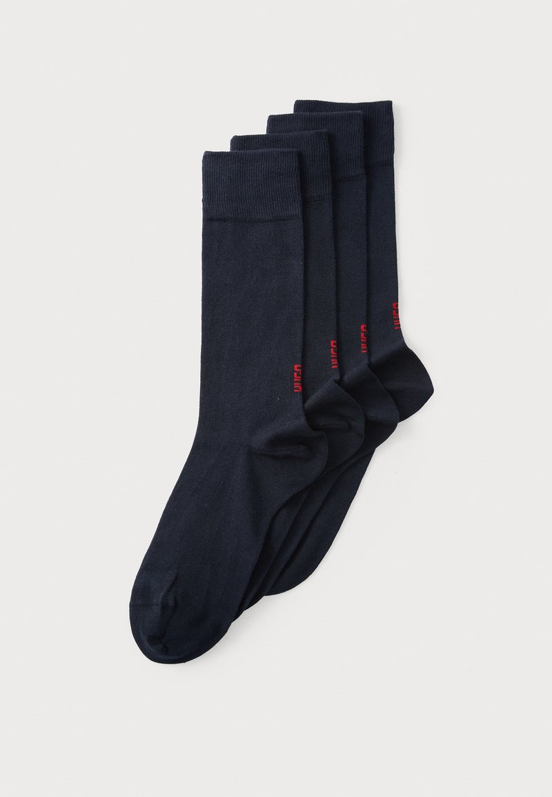 Mørkeblå bomuldsokker i en pakke med fire. Ribbet kant ved anklen og rød mærkelogo tæt på anklen. Glat tekstur med et klassisk design.