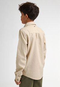 Beige overhemd met lange mouwen en een klassieke kraag, met knoopmanchetten, een effen textuur en een klein merketiket onder de kraag aan de achterkant.