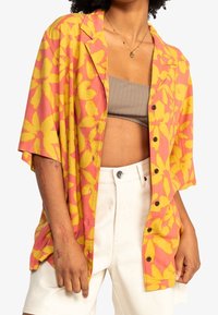 Short-sleeve button-up shirt with pink and yellow floral pattern, fabric with a smooth texture, and black buttons along the front.