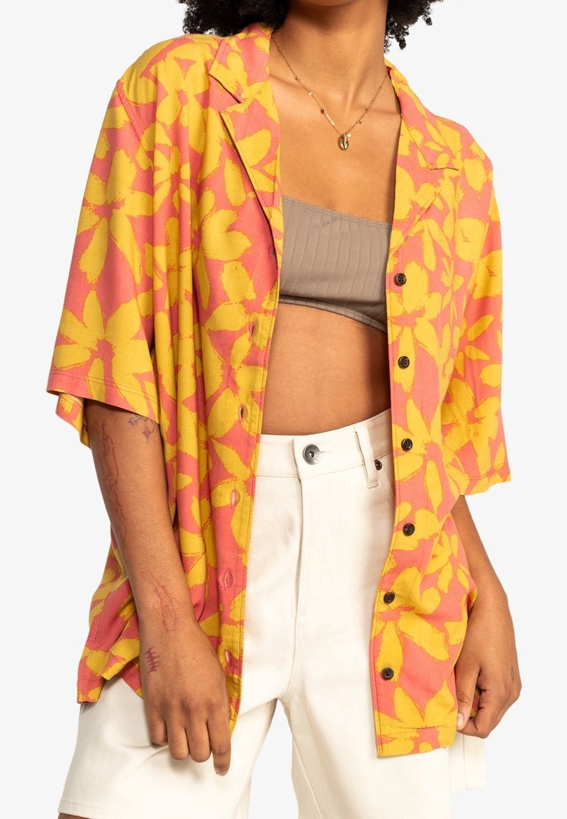 Short-sleeve button-up shirt with pink and yellow floral pattern, fabric with a smooth texture, and black buttons along the front.