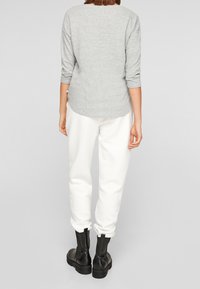 Gray long-sleeve top, white textured joggers, and black lace-up ankle boots. Solid colors with a casual fit and subtle stitching details.