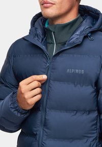 Granatowa puchowa kurtka z kapturem, z pikowanymi elementami, zamkiem błyskawicznym oraz logo 'ALPINUS' na piersi. Gładka faktura.