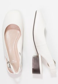 Chaussures à bride arrière blanches avec un bout rond, un extérieur en cuir lisse, un petit talon carré et un accent en boucle en métal. Coutures discrètes visibles.