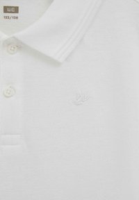 Biela textúrovaná polokošeľa s golierom, dvoma gombíkmi a jemným vyšitým logom vtáka na hrudi.