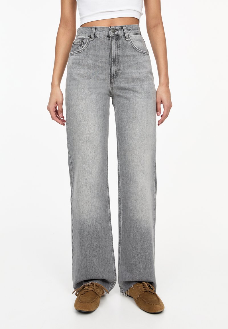 Jeans cu talie înaltă, cu picioare largi, din denim gri deschis, cu secțiuni decolorate. Include buzunare frontale și urechi pentru curea. Textură moale, croială lejeră.
