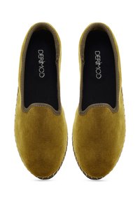 Para musztardowoy żółtej zamszowej obuwia wsuwanego z brązowymi detalami i czarnymi wkładkami oznaczonymi "DERIMOD", pokazane z góry na białym tle.