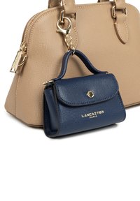 Borsa a tracolla beige con texture e hardware dorato, accompagnata da una piccola pochette in pelle blu navy con patta e logo dorato.