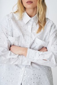 Hvitstripet button-up skjorte prydet med sølvfargede paljetter, med krage og to frontlommer, samt en avslappet passform.