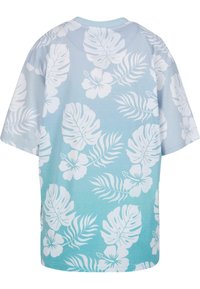 Camiseta de manga corta en azul claro con efecto degradado, que presenta un patrón de hojas tropicales y flores en blanco. Fabricada en suave tela de algodón.