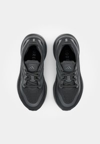 Black athletic shoes with a textured mesh upper, rounded toe, supportive midsole, and matching laces, featuring the Adidas logo.