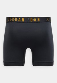 Boxers de algodón negros con una cintura elástica negra que lleva el texto "JORDAN" en amarillo. Textura suave, diseño ajustado y longitud hasta la mitad del muslo.