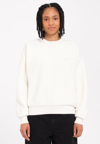 Hvid fleece sweatshirt med rund halsudskæring, ribbede manchetter og kant, samt et lille broderet logo på brystet. Blød tekstur, afslappet pasform.