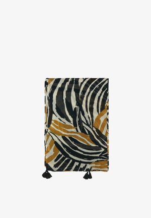 Tissu plié avec des rayures abstraites noires, blanches et marron rappelant un zèbre, avec des pompons noirs sur deux coins.