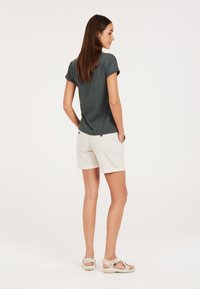 T-shirt grigio a maniche corte, pantaloni corti beige chiaro con risvolti e sandali beige. L'outfit presenta una vestibilità comoda e tasche funzionali.