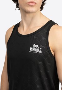 Črna brezrokavna majica s subtilnim vzorcem in belim logotipom "Lonsdale London" na prsih. Narejena je iz gladkega, lahkega materiala.