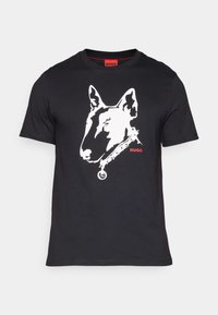 T-shirt noir avec un graphisme blanc représentant la tête d'un chien, avec un design de collier. "HUGO" est imprimé en rouge sous le graphisme. Manches courtes.