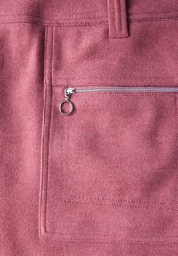 Rosa filt tyg med en slät yta, som har en rektangulär ficka och en mindre dragkedjeficka med en rund dragflik.