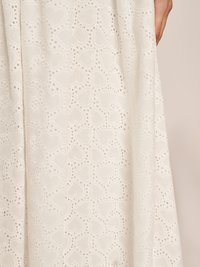 Tecido de renda branca com um padrão intrincado de corações com pequenos recortes, criando uma aparência delicada e texturizada.