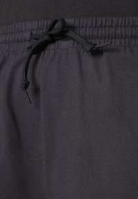 Black drawstring waistband with a textured finish. Made of soft, stretchy fabric with a relaxed fit, designed for comfort and ease.