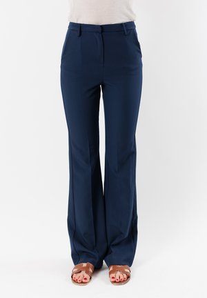 Pantaloni blu navy a vita alta con design a gamba larga e texture liscia. Presenta tasche frontali e delicate pieghe. Indossati con sandali marroni.