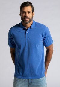 Modrá polokošile s límečkem a zapínáním na dva knoflíky, vyrobená z texturovaného materiálu. Krátké rukávy a rovný lem.