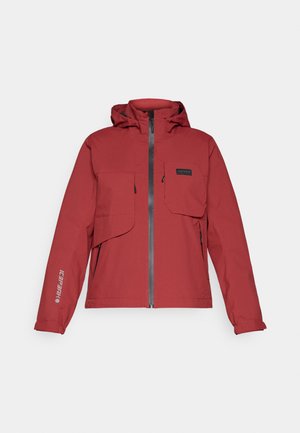Veste imperméable rouge avec fermeture éclair, capuche ajustable, deux poches avant et un logo sur la manche gauche. Texture lisse.