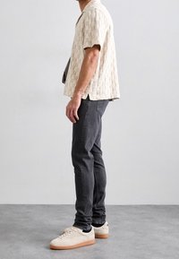 Lyhythihainen, teksturoidusta beigest ä valmistettu paita, hoikat mustat farkut ja kermaiset tennarit kumipohjilla. Yksinkertainen muotoilu, rento istuvuus ja hienovaraiset yksityiskohdat.