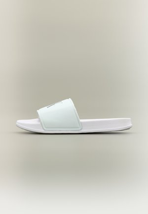 Hvit tøffelsandal med teksturert såle og bred stropp med et svakt svart logo over en nøytral bakgrunn.